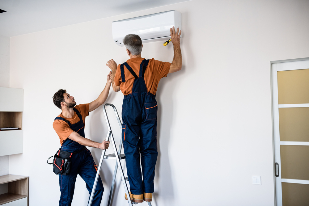 Two,workers,in,uniform,,air,conditioning,masters,using,ladder,while